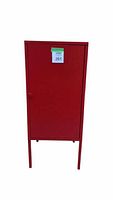 Front view of the closed candy apple red metal cabinet showing tall legs and simple door with handle