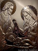 Close-up of the detailed silver etching showing the faces and upper bodies of Mary, Joseph, and baby Jesus with halos on a wooden base.