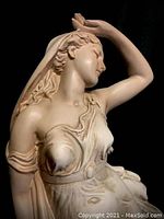 Close-up of upper half of alabaster statue showing drapery and figure from side angle.