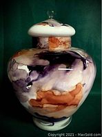 Full view of Murano glass urn with lid on, showing marbled color pattern in purple, amber, and white.