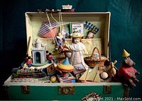 Open treasure chest music box showing detailed 3D toys including doll, horse, castle soldiers, tops, and other vintage toy figures inside.