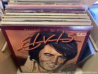Box of mixed vinyl records, visible album cover of Elvis Presley - Welcome to My World