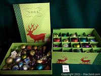 Green storage box containing multiple multicolor Christmas ornaments, some loose and some compartmentalized