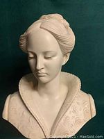 Close-up of the woman bust statue's face and upper chest area showing detailed hair and garment patterns.