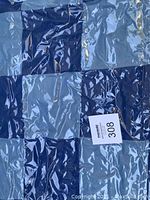 Close-up of quilt patchwork pattern showing different shades of blue and gray squares.