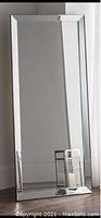 Photo of tall rectangular full length mirror with beveled edge mirrored frame reflecting floor, wall and curtain.