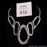 Front view of the Mid-Century Modern silver necklace on black display showing five large irregular oval links.