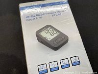 Box for Homiee Blood Pressure Monitor BP1002, shows model and features including DC power port, irregular heartbeat detector, wrist cuff feature, and memory storage slot