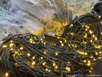 Close-up of warm white string lights with dark green wire, powered on.