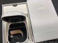 Set of hearing aids inside their charging case, placed in the original white branded box.