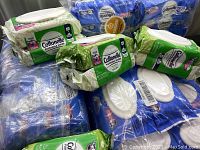 Lot of multiple Cottonelle Flushable Wipes packs, mainly green and white packaging with resealable lids, arranged in stack.