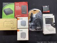 All items arranged on a black surface showing brands and packaging: Linkfor splitter, Mpow wireless transmitter, wireless adapters, Joyo mini amp, audio converter.