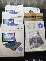 Photo of boxed keyboard cases and wireless keyboard packaging for tablets, including 2 Typecase Flexbook 6-in-1 keyboard cases and others.