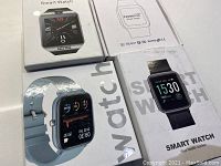 Four smart watches in original boxes showing different models and packaging.