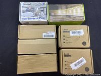 Boxes showing RGBW cabinet spotlight from Ifeland and multiple LED puck lights in cardboard packaging.