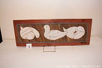 Full view of the wooden framed wood lath painting showcasing three white ducks on a brown and gray wooden background.