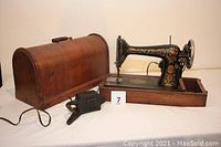 Front view of sewing machine in wooden base, bentwood case lid removed, knee switch visible