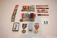 Full view of 15 medals arranged in groups with matching ribbons laid out around.