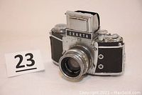 Front angled view showing camera body with lens and EXAKTA name plate on prism viewfinder.