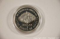 Front side of the 1987 Proof Constitution Bicentennial Silver Dollar showing the inscription 'E Pluribus Unum', 'United States of America', and a group scene of signers of the Constitution.