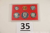 Front view of sealed plastic case showing six coins and lot number card
