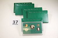 Five proof sets in green folders, one opened showing coins in plastic case.