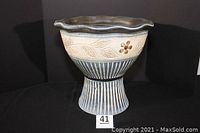 Front view of large footed jardiniere planter with floral relief and striped pedestal base