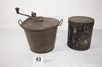Full view of antique bread maker with hand crank and clamp base alongside hinged lid metal tin