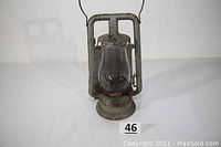 Front view image of grey painted carriage lantern with clear bulls-eye glass globe and bail handle, showing entire lantern and base with metal clip