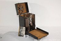 Vintage Revere Model 80 8-mm projector open inside original carrying case with manual beside it.