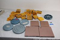 Photo showing a spread of metal film reels, yellow cardboard Kodak film boxes, and several large cardboard storage boxes for films.