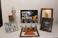 Lot shows all items arranged against a wall: MASH 4077 vodka dispenser, four pilsner glasses, Garfield mirror, Jack Daniels framed sign, 3 Stooges print, Revolutionary War soldier drawing, and double-sided Foamboard sign.