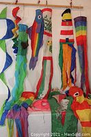 Wide view showing multiple hanging multicolor wind socks in various shapes including fish and spiral designs.