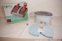 Homedics Shiatsu Pro Foot Massager in original box with Revlon Paraffin Bath and blue mitts placed in front on white cloth surface.
