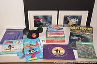 Photo of entire Disney lot showing books, Mickey Mouse ears hat, framed prints, records, and bags spread on a surface.
