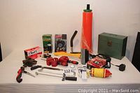 Complete overview of all lot items arranged on a table including pallet wrapper, clamps, lights, tools, and storage box.