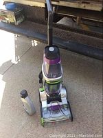 Front view of upright cleaner with cleaning solution bottle beside it