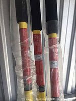 Photo showing three long yellow and black support poles with cushioned handles wrapped in plastic