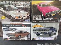 Four model car kits displayed with visible brand and model names and artwork depicting classic muscle cars: Mustang SVO, Dodge Charger, Plymouth HEMI Cuda.