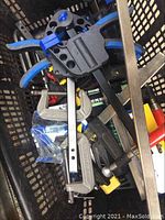 Initial overview photo of mixed clamps in basket showing a variety of clamps including blue and black plastic quick release and metal C clamps.