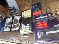 Overview of drill bits sets, screwdrivers, and electronic caliper in packaging