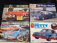 Four vintage model car kits showing box fronts: '53 Chevy (Monogram), '69 Dodge Charger (Revell Monogram), Richard Petty Pontiac Grand Prix (Monogram), Richard Petty Grand Prix Stock Car (AMT ERTL).
