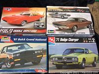 Top view of four model car kit boxes with artwork showing Dodge Daytona, Buick Grand National, and two Dodge Chargers