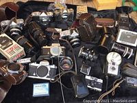 Wide view of all camera bodies, lenses, cases and boxes laid on black cloth