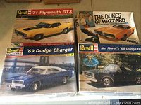 Four vintage model car kits laid out on a surface showing original box art and condition.