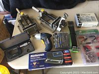 Photo showing two metal woodworking clamps, cordless electric screwdriver, Mastercraft electronic caliper in box, precision screwdriver set, 23-piece accessory kit in box, and 28-piece electrical clip kit.