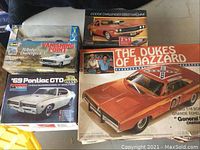 Four vintage model car kits in original boxes including Dodge Challenger R/T, Dodge Challenger Street Machine, '69 Pontiac GTO, and The Dukes of Hazzard General Lee Charger.