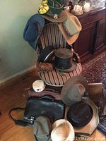 Green cap, beige fedora, blue fedora on chair back with taupe fedora below