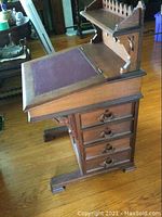 Side view of desk showing four stacked drawers, slanted writing surface and gallery shelf