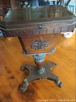 Front view of stand showing octagonal hinged top and carved apron.